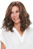 Happy woman with Alopecia showing her brunette Clair wig with romantic loose waves 
