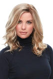 Young woman with fine hair wearing a blonde wavy Clair wig that is just below the shoulders 